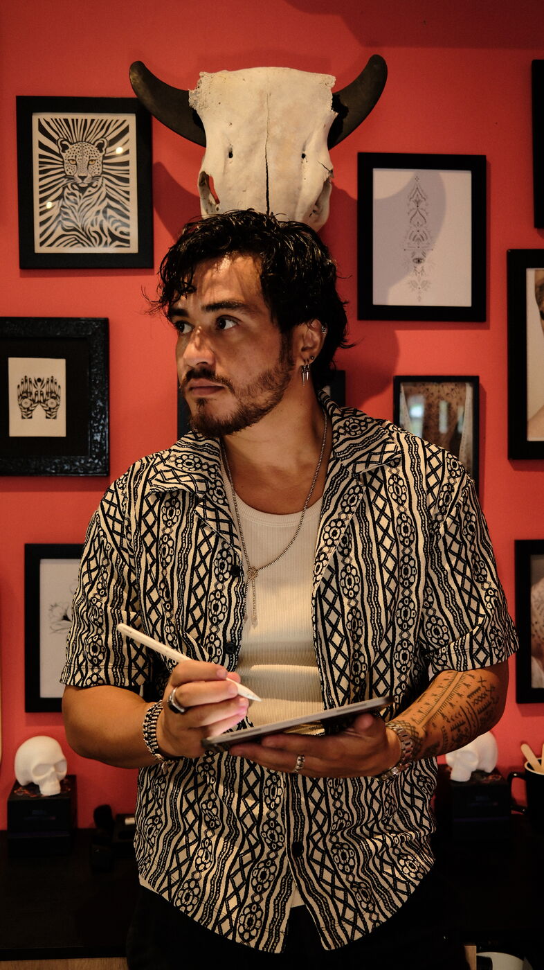 Soane Patita, tatoueur, dans le studio MANUIA à Saint-François, tablette à la main